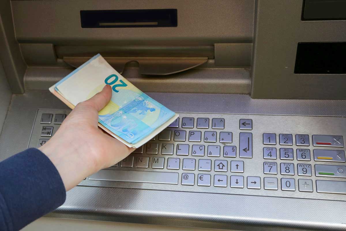 A person pulls out bank notes from an ATM in Europe