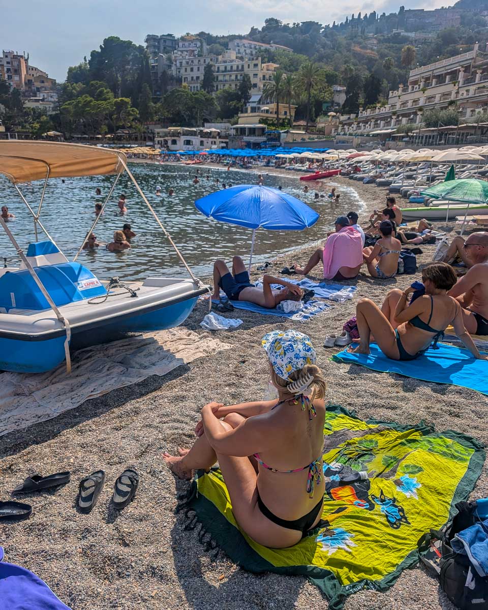 Bailey-sitting-on-Mazzaro-beach-in-Taormina-Italy
