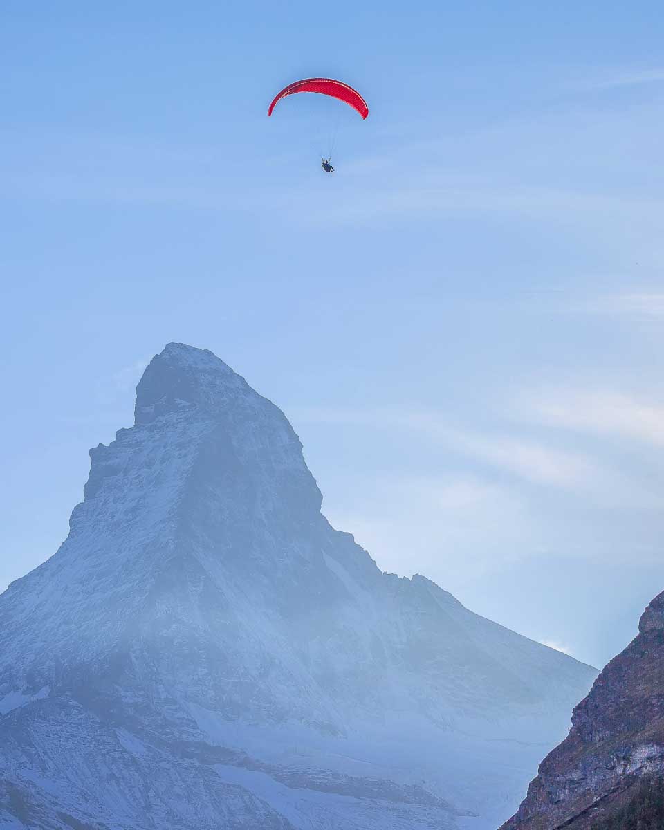 A person paraglides by the Matterhorn in Zermatt Switzerland summer