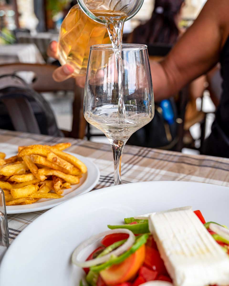 A salad and fries with wine eaten on a food tour in Cyprus