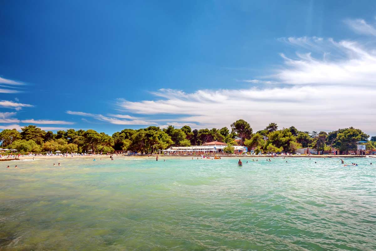 People swim at the beach in the ocean in Borik, Zadar, Croatia
